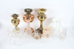 Two brass oil lamps, together with a copper example and various shades and chimneys (qty)