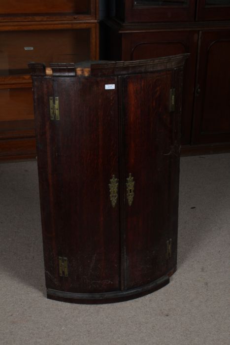 George III oak and mahogany crossbanded bow front hanging corner cupboard, the two doors opening