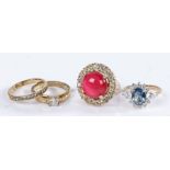 A collection of four yellow metal costume rings with white, red and blue coloured stones. Gross