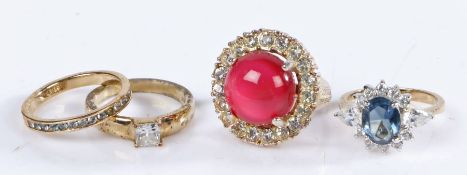 A collection of four yellow metal costume rings with white, red and blue coloured stones. Gross