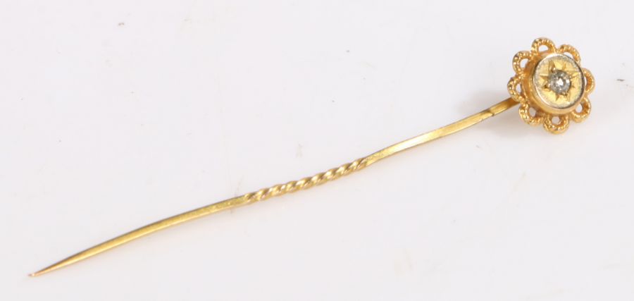 A 9ct yellow gold stick pin, the floral head set with one round cut diamond. Approx. diamond carat