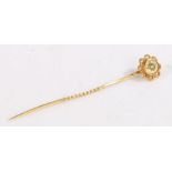 A 9ct yellow gold stick pin, the floral head set with one round cut diamond. Approx. diamond carat