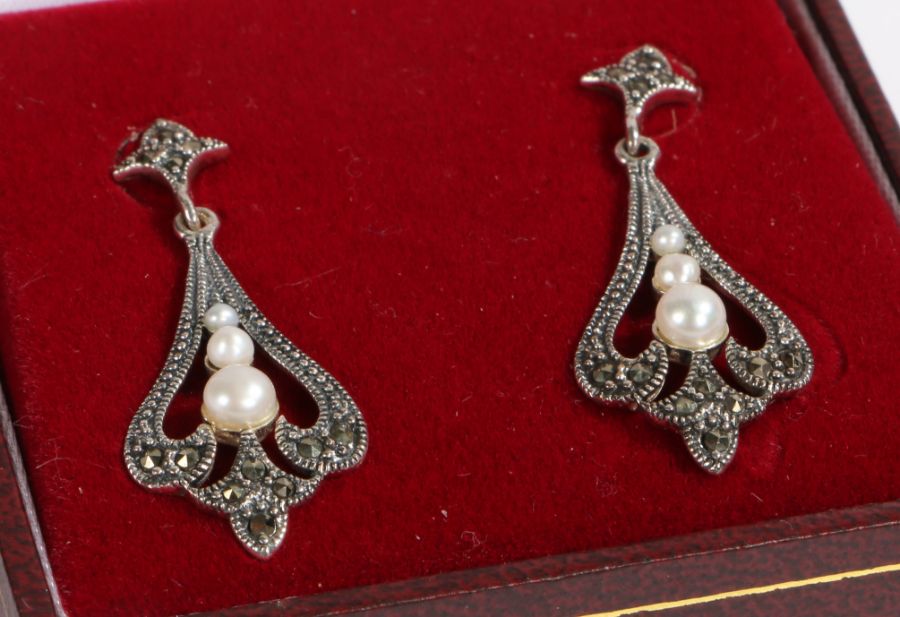 A pair of art deco style drop earrings set with pearls. Encased in a jewellery box.