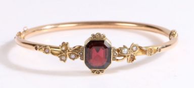 A 9ct yellow gold hinged bangle set with one octagonal cut garnet. Approx. measurements: 12.00 x