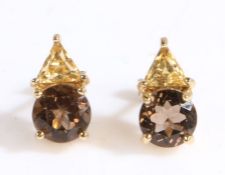A pair of 9ct yellow gold stud earrings with citrine and smokey quartz. Approx. 12.90 x 7.00mm.