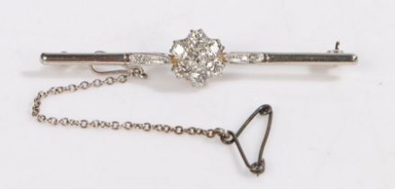 A platinum bar brooch with a flower shaped diamond cluster and safety chain. Approx. total diamond