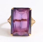 A yellow gold ring set with one emerald cut stone. Stone unknown. Brownish red showing pleochroism -