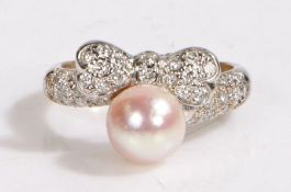 A white metal diamond bow shaped ring with one pinkish pearl. Approx. total diamond carat weight:
