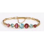 A 14ct yellow gold bracelet set with garnet and aquamarines. Approx. length 19cm. Weighing 6.70