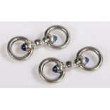 A pair of platinum Cartier stirrup cuff-links with a blue sapphire cabochon at each end. Stamped