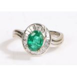 An 18ct white gold oval cut emerald and diamond cluster ring. Approx. emerald carat weight: 1.15cts.