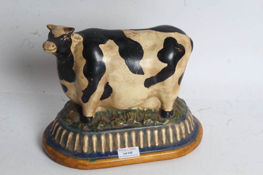 20th century pottery cow, in the folk art style, with a naturalistic base, 26cm wide