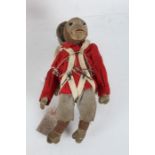 Early to mid 20th century straw filled monkey, in red military uniform, bearing label "I do  not