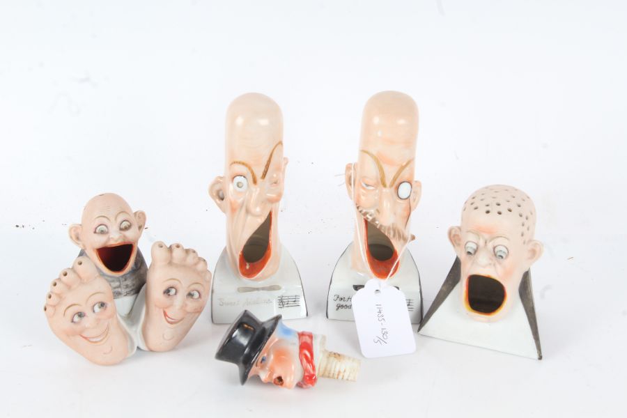 Five items of porcelain, to include two pin holders, and a bottle stopper, in the form of humorous