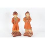 Pair of Art Deco plaster figures, each in the form of a young girl and boy in orange outfits, 31cm