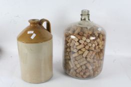 Large stoneware flagon together with a large glass bottle full of wine corks (2)