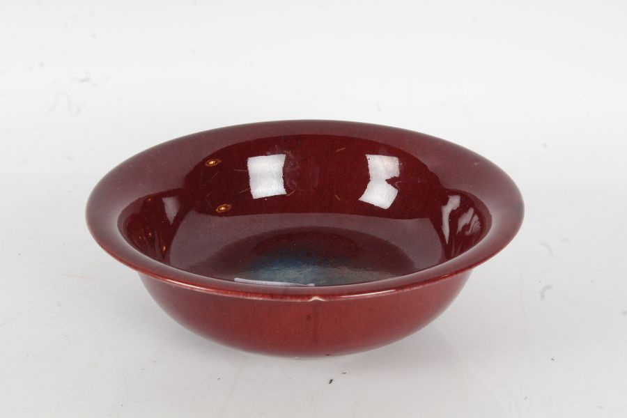 Chinese sang de boeuf bowl, the flared rim above a tapering bowl, raised on a pierced hardwood