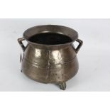 17th Century bronze cauldron, the flared rim above two angular handles and bulbous body, raised on