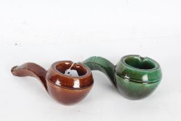 Two Dunhill pottery novelty ashtrays, each in the form of pipes, in green and brown glaze (2)