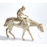 Silver coloured metal sculpture depicting a horse and jockey, 49cm wide, 40cm high
