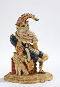 Victorian cast iron Mr Punch doorstop, modelled seated on a stack of books with dog wearing a plumed