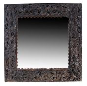 A late 19th Century heavily carved oak framed mirror, the mirror plate within the berry and leaf