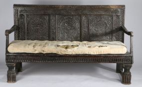 An oak bench, 17th Century and later elements, the lunette carved top rail above three flower and
