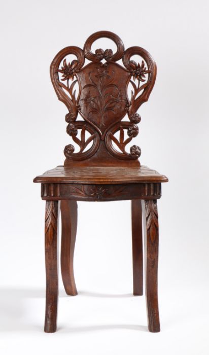 Black Forest child's musical chair, the scrolling top rail above a carved shield back and hinged