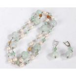 A carved jade necklace with intersecting pearls, the jade carved into flower heads, with a