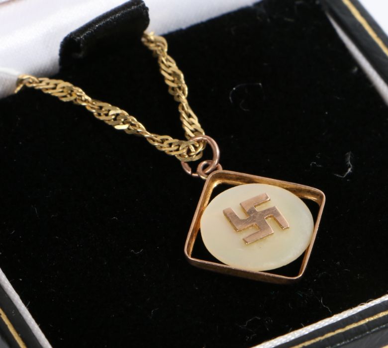 A 9 carat yellow gold pendant with a Swastika set on mother of pearl suspended from a 9 carat yellow