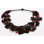 An art deco necklace with four rows of rectangular black beads intersected by spherical red beads,