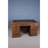 A 20th century oak twin pedestal desk with a brown leather inset top above nine drawers raised on