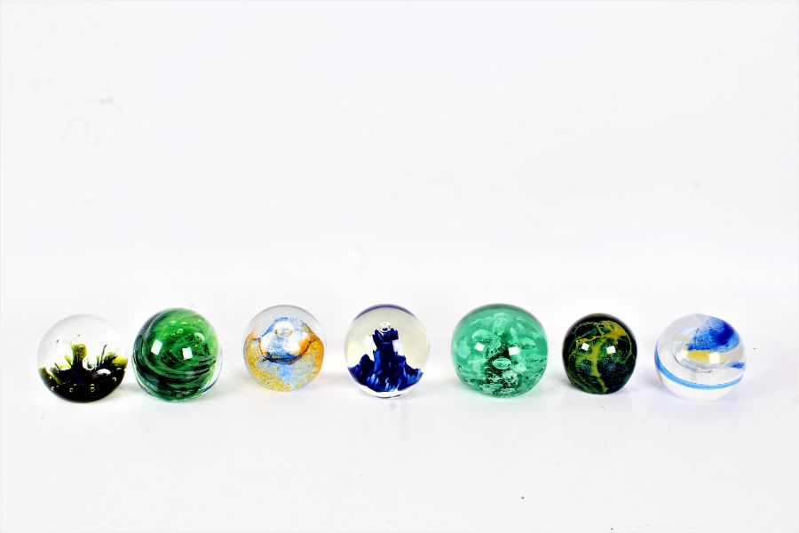 Seven glass paperweights to include a Victorian end of day green glass paperweight two Cathness