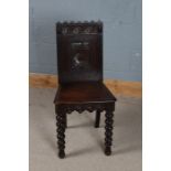 A 19th century carved oak hall chair, with a wavy cresting rail above three circular lozenges and