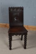 A 19th century carved oak hall chair, with a wavy cresting rail above three circular lozenges and