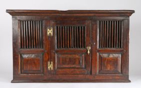 An oak mural glass/livery cupboard, the rectangular top above the concave cornice and slated front