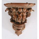 18th Century walnut wall bracket, the shaped shelf above carved depictions of dancing putti