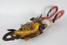 20th century African mask, with two pink horns above two ram style horns going down to an