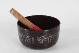 Indian metal singing bowl together with stick, the bowl with a Buddha to the base, 15cm diameter