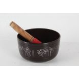 Indian metal singing bowl together with stick, the bowl with a Buddha to the base, 15cm diameter