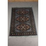 Middle Eastern rug, the blue and cream ground with three diamond lozenges and floral decoration,