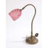 Brass reading lamp, with mottled puce and white glass shade mounted to a curved arm and circular