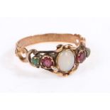 A yellow metal and opal ring, the head set with a oval opal with garnets and emeralds to the