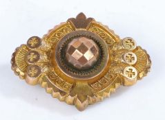 A yellow metal brooch, with a center design with fleur de lis, with a glass back panel containing