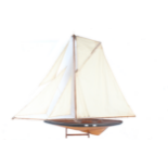A large 20th century wooden pond yacht, with a single mast, weighted hull, canvas sails, rigging set