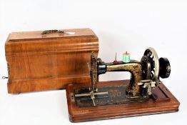 Frister Rossman manual sewing machine, the black body with foliate decoration, housed in a marquetry