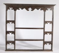 An oak plate rack, 18th Century elements, the concave cornice above an undulating apron and a series