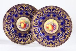 Pair of Royal Worcester porcelain plates hand decorated by T. Nutt and R. Price, the blue ground