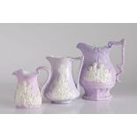 Three early to mid 19th Century lilac relief moulded jugs, the first by Samuel Alcock depicting