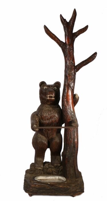 A Folk Art carved standing bear stick stand, the bear with wide eyes and an pen mouth holding onto a